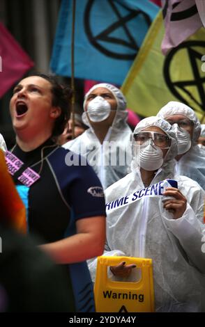 Londra, Inghilterra, Regno Unito. 28 ottobre 2024. I manifestanti gridano e ondate bandiere come parte della dimostrazione, alcuni vestiti con tute di nocciola. Extinction Rebellion (XR) cammina per la City di Londra e fermati e dimostra fuori dagli uffici delle compagnie di assicurazione che continuano ad assicurare le compagnie di combustibili fossili nonostante gli avvertimenti di una crisi climatica da parte degli scienziati. I manifestanti credono che se le compagnie assicurative cessassero il loro coinvolgimento con queste compagnie avrebbero lottato per continuare a lavorare con le mie. L'azione è la prima di una settimana di protesta diretta specificamente al settore assicurativo. Foto Stock