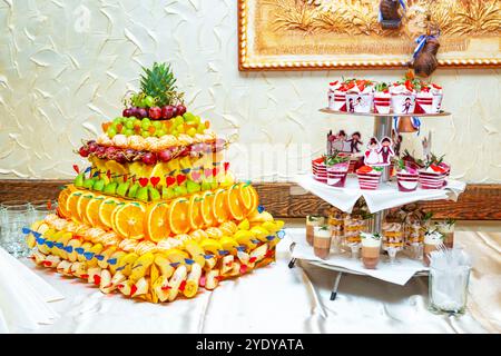 Una vivace esposizione di frutta assortita disposta in una torre visivamente attraente in un raduno festoso, che mostra creatività e freschezza. Foto Stock