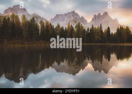 Tranquilli riflessi di alberi autunnali e dei monti Cadini di Misurina all'alba sulle calme acque del Lago d'Antorno nelle Dolomiti italiane. Foto Stock