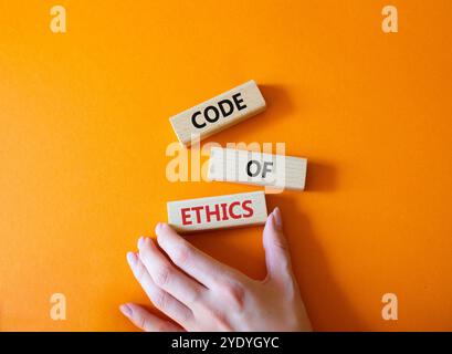 Simbolo del codice etico. Parole concettuali codice etico su blocchi di legno. Bellissimo sfondo arancione. Mano d'affari. Business and Code of Ethics Conce Foto Stock