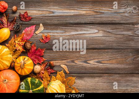 Raccolta autunnale e sfondo del Ringraziamento. Zucche, foglie secche cadute, noci, castagne su fondo rustico in legno. Posizione piatta. Vacanze autunnali Foto Stock