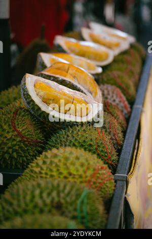 Mostra di frutta duriana al mercato locale. Alcuni dei frutti duriani sono aperti per rivelare la polpa gialla all'interno. Foto Stock