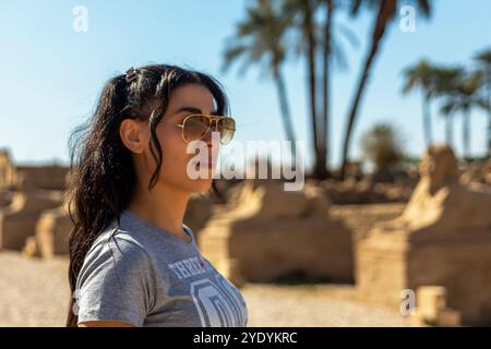 Turista che si gode la magia dell'antico Egitto passeggiando lungo il viale delle Sfingi a Luxor. Seguendo le orme dei faraoni e ammirando Foto Stock