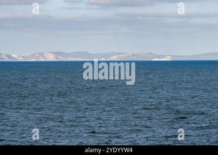 Una nave lascia Portland Harbour attraverso Weymouth Bay, con le scogliere della Jurassic Coast del Dorset alle spalle. Foto Stock