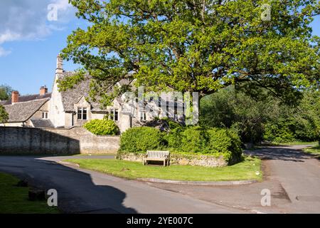 Cottage tradizionali in pietra del Cotswold accanto all'incrocio di due stradine di campagna nel villaggio di Coln St Dennis nel Gloucestershire. Foto Stock