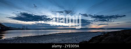 Il sole tramonta sul secondo ponte di Severn Crossing e sulle colline del Monmouthshire, viste dalla spiaggia di Severn a Bristol. Foto Stock