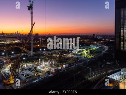 Il sole tramonta su un cantiere all'Olympic Park di Stratford, East London, con lo skyline della City of London alle spalle. Foto Stock