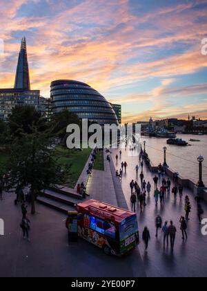 I turisti camminano lungo la sponda sud del Tamigi a Southwark, Londra, al tramonto. Foto Stock