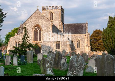 Il sole splende sull'esterno in selce della tradizionale chiesa parrocchiale inglese di St Mary a Great Bedwyn, Wiltshire. Foto Stock