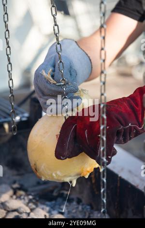 Primo piano delle mani di un uomo che taglia un pezzo di caciocavallo, un tipico formaggio affumicato del sud Italia a Melfi, Basilicata Foto Stock