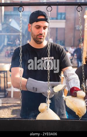 Uomo italiano che taglia un pezzo di caciocavallo, un tipico formaggio affumicato del sud Italia a Melfi, Basilicata Foto Stock