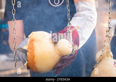 Primo piano delle mani di un uomo che taglia un pezzo di caciocavallo, un tipico formaggio affumicato del sud Italia a Melfi, Basilicata Foto Stock