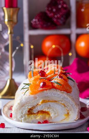 Rotolo di meringa ripieno di mascarpone, crema e marmellata di mandarini, decorato con mandarini e semi di melograno. Dessert per San Valentino, mandarino Foto Stock