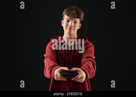 Adolescente che gioca a videogame con controller su sfondo nero Foto Stock