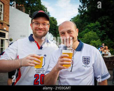 Lymm Food Festival 2024 - due uomini in Coppa del mondo FIFA Inghilterra magliette bere pinte di alcol Foto Stock