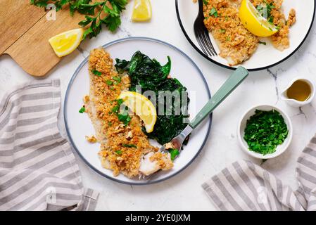 Filetto di merluzzo al forno sotto una crosta di formaggio di noci con spinaci stufati. Focalizzazione superiore a veiw.selective Foto Stock