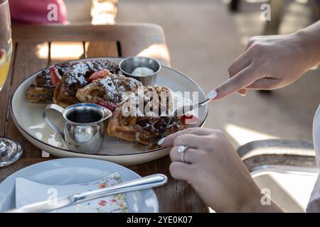 I waffle belgi leggermente spolverati con zucchero a velo e sciroppo d'acero sono un dolce pasto per la colazione. Foto Stock