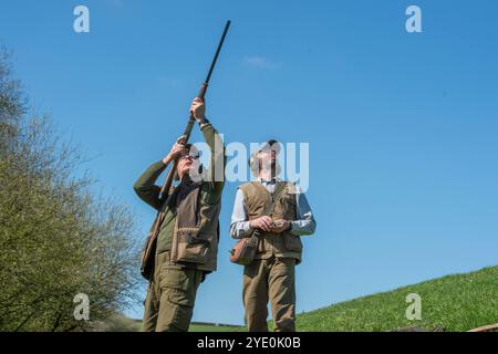 uomo che sparava ai fagiani, puntando in alto, con il suo caricatore Foto Stock