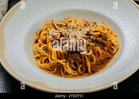 Spaghetti classici bolognesi conditi con parmigiano, serviti in un ambiente elegante Foto Stock