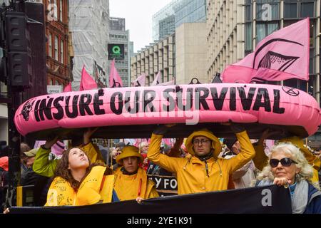 Londra, Regno Unito. 28 ottobre 2024. Gli attivisti marciano con una barca gonfiabile segnata con "assicurati la nostra sopravvivenza" mentre la ribellione dell'estinzione inizia tre giorni di proteste nella City di Londra, il distretto finanziario della capitale, chiedendo alle compagnie assicurative di smettere di assicurare progetti di combustibili fossili. (Foto di Vuk Valcic/SOPA Images/Sipa USA) credito: SIPA USA/Alamy Live News Foto Stock