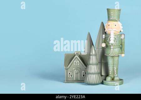 Decorazione natalizia verde menta con schiaccianoci, alberi e casa su sfondo blu con spazio per copie Foto Stock