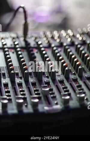 Primo piano di una console di mixaggio audio con lettori e manopole in condizioni di scarsa illuminazione Foto Stock