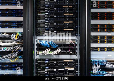 Illustrazione di file e colonne di data center con dischi rigidi e cavi durante la sua visita al sito del data center aziendale di Scaleway. Allo scopo di discutere le questioni di implementazione del data center e le condizioni per rendere più ecologiche queste infrastrutture, in particolare per quanto riguarda il consumo energetico. In effetti, Scaleway dispone di data center che utilizzano il 100% di energia rinnovabile. Il più recente data center DC5 utilizza un sistema di raffreddamento adiabatico basato sull'evaporazione dell'acqua e che evita la necessità di aria condizionata. 28 ottobre 2024, a Saint-Ouen-l'Aumone (Val-d'oise) vicino a Parigi. Foto di Alexis Jumeau/ABACA Foto Stock