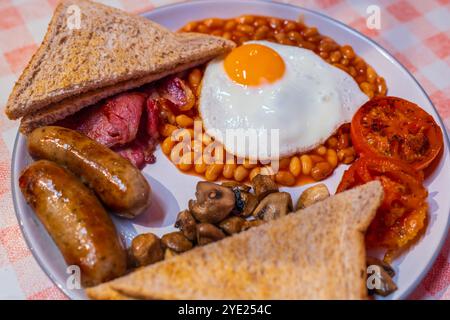 Colazione all'inglese con uova fritte, salsicce, pancetta, fagioli, toast e tomati Foto Stock