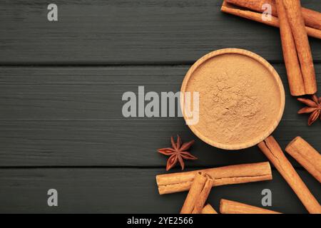 Bastoncini di cannella su sfondo di legno nero. Spezie alla cannella nel recipiente. Cannella di Ceylon. Foto Stock