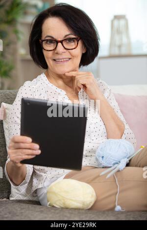 donna anziana di sessant'anni che utilizza un tablet digitale in interni Foto Stock