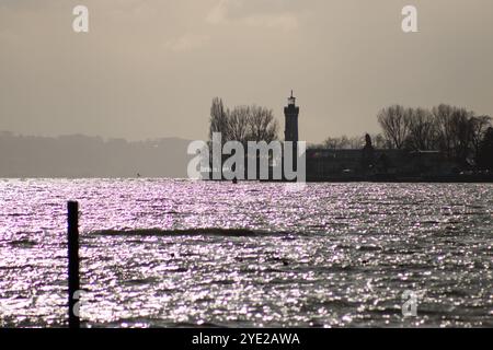 Sagoma del faro Lindau sul lago di Costanza, con acque scintillanti e un cielo nuvoloso sullo sfondo. Foto Stock