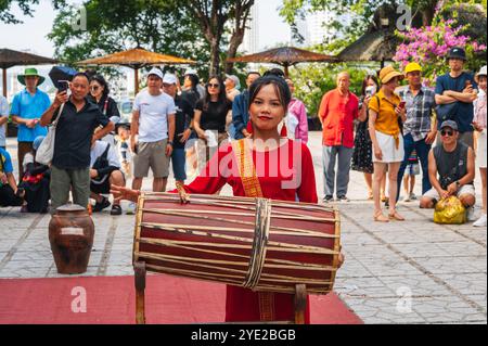 Ritratto di una giovane donna vietnamita in un abito rosso che suona un tamburo tradizionale alle po Nagar Cham Towers di Nha Trang in Asia. Nha Trang, Vietnam - 8 agosto 2024 Foto Stock