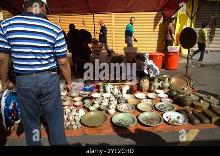 Un uomo che presta attenzione al gres di porcellana ad un venditore durante il mercato domenicale di Gaya su Gaya Street, Kota Kinabalu, Sabah, Malesia. Foto Stock