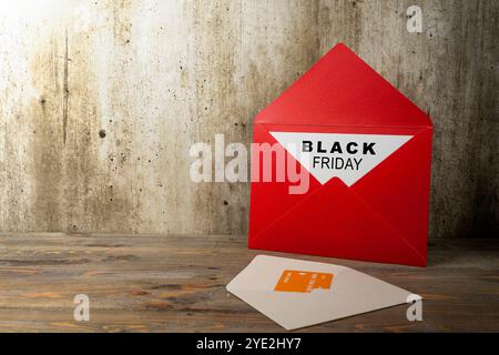 Busta rossa e cartolina con carta bianca con scritta Black Friday e carta di credito sullo scaffale. Offerta Black Friday Foto Stock