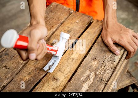 I lavoratori che indossano giubbotti di sicurezza utilizzano il martello per lavorare smontando le parti del pallet. La scena è ambientata in uno sfondo di magazzino. Fabbrica di lavorazione del legno Foto Stock