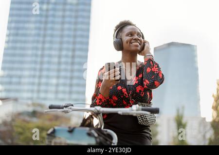 Ritratto di una giovane donna sorridente con la sua bicicletta in città Foto Stock
