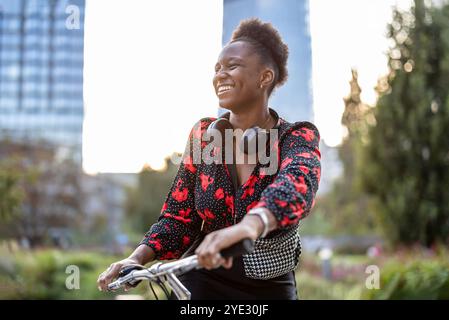 Ritratto di una giovane donna sorridente con la sua bicicletta in città Foto Stock