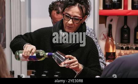 Durante il Festival del Tartufo d'Alba in Italia, una donna versa il vino in un bicchiere mentre i visitatori assaggiano tartufi locali e delizie culinarie. Foto Stock