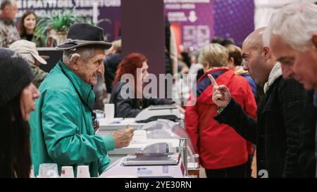 Al Festival del Tartufo d'Alba in Italia, la folla si riunisce per sperimentare le offerte uniche di tartufi della regione, con i venditori impegnati in vivaci discussioni Foto Stock