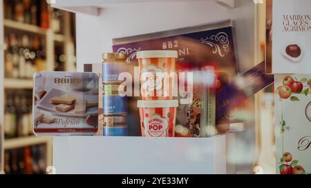 Un vivace espositore con vari prodotti alimentari è disposto su uno scaffale. Gli articoli includono caramelle, gelati e dolci tradizionali Foto Stock