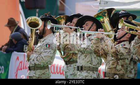 Musicisti in uniforme militare suonano energicamente strumenti di ottone, riempiendo l'aria di suoni vibranti durante un festival locale ad Alba, Italia, Foto Stock