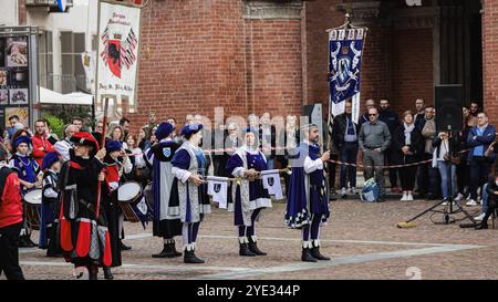 Un vivace gruppo di artisti vestiti con costumi tradizionali suona strumenti e tiene striscioni, intrattenendo la folla durante un festival vivace Foto Stock