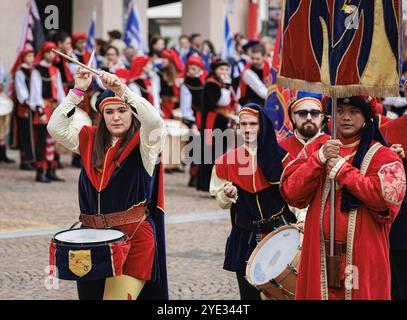 I partecipanti vestiti con costumi tradizionali si esibiscono con la batteria durante un vivace festival ad Alba, in Italia, mettendo in mostra la cultura e la musica locali come meglio credono Foto Stock