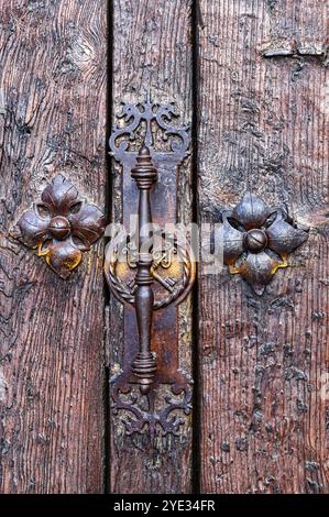 Avila, Spagna - 11 febbraio 2023: Maniglia e rivetti metallici medievali sulla superficie in legno di un'antica porta. Foto Stock