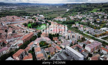 Una prospettiva aerea cattura la pittoresca cittadina di Alba, in Italia, mettendo in evidenza la sua architettura unica e gli splendidi paesaggi verdi contro una nuvola Foto Stock
