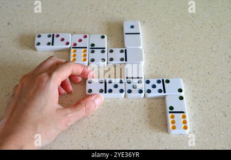 La persona sta giocando a domino su sfondo chiaro. Foto Stock