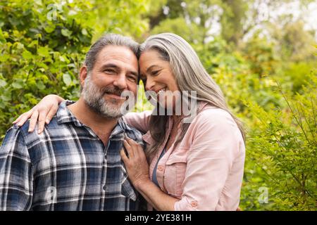 Coppia matura felice che abbraccia all'aperto, si gode la natura e sorride calorosamente insieme Foto Stock