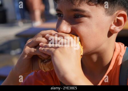 preadolescente che prende un boccone di un delizioso hamburger Foto Stock