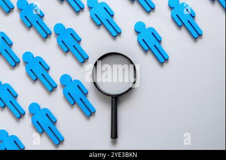 Una lente d'ingrandimento con una fila di figure blu. Copia spazio per il testo. Selezione, concentrazione, attenzione e ricerca del concetto di persona giusta. Foto Stock