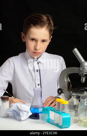 Un ragazzo scienziato ricercatore con un microscopio conduce esperimenti in laboratorio. Lo studente studia biologia e chimica. Scienza e istruzione. Foto Stock